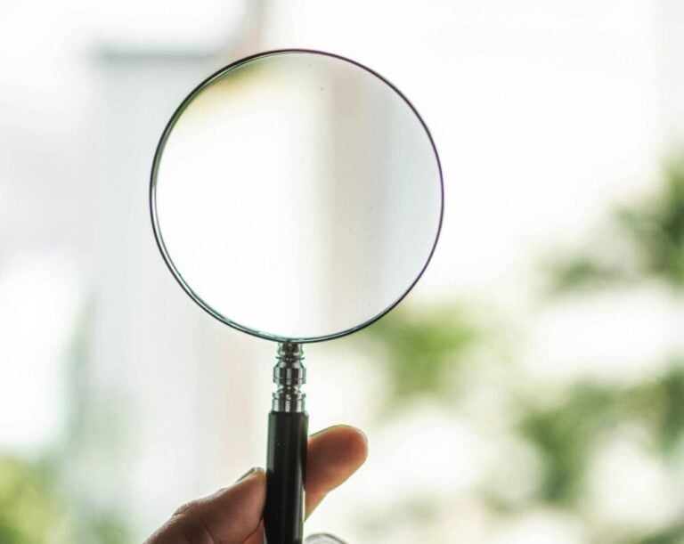 Magnifying glass representing the pressure professionals feel when their reputation and decisions are constantly scrutinized