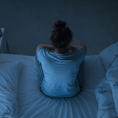 Sunday night anxiety. A woman sitting on the edge of her bed, worried about work and overthinking