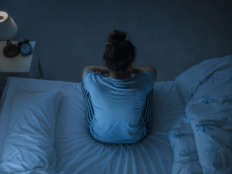 Sunday night anxiety. A woman sitting on the edge of her bed, worried about work and overthinking