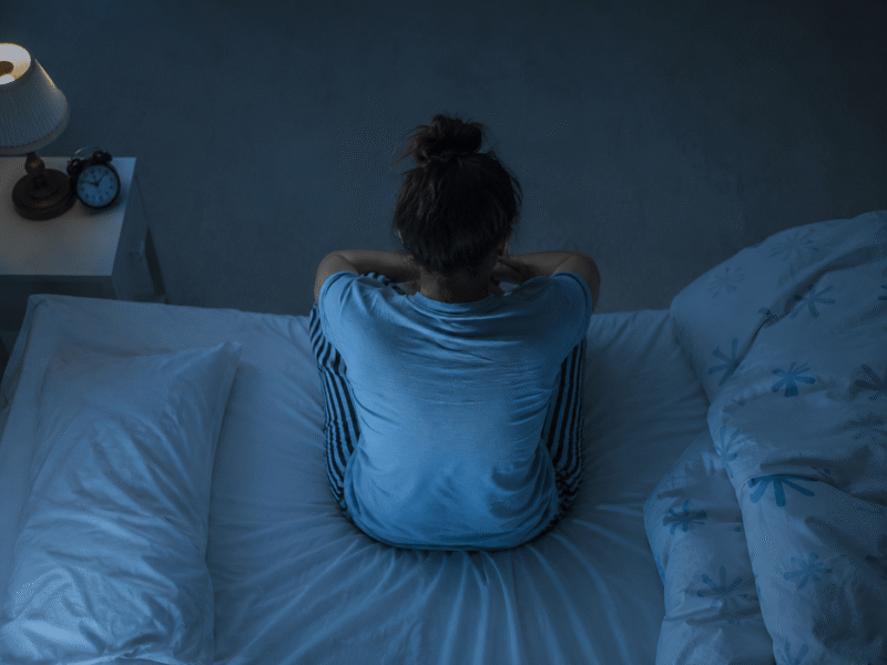 Sunday night anxiety. A woman sitting on the edge of her bed, worried about work and overthinking