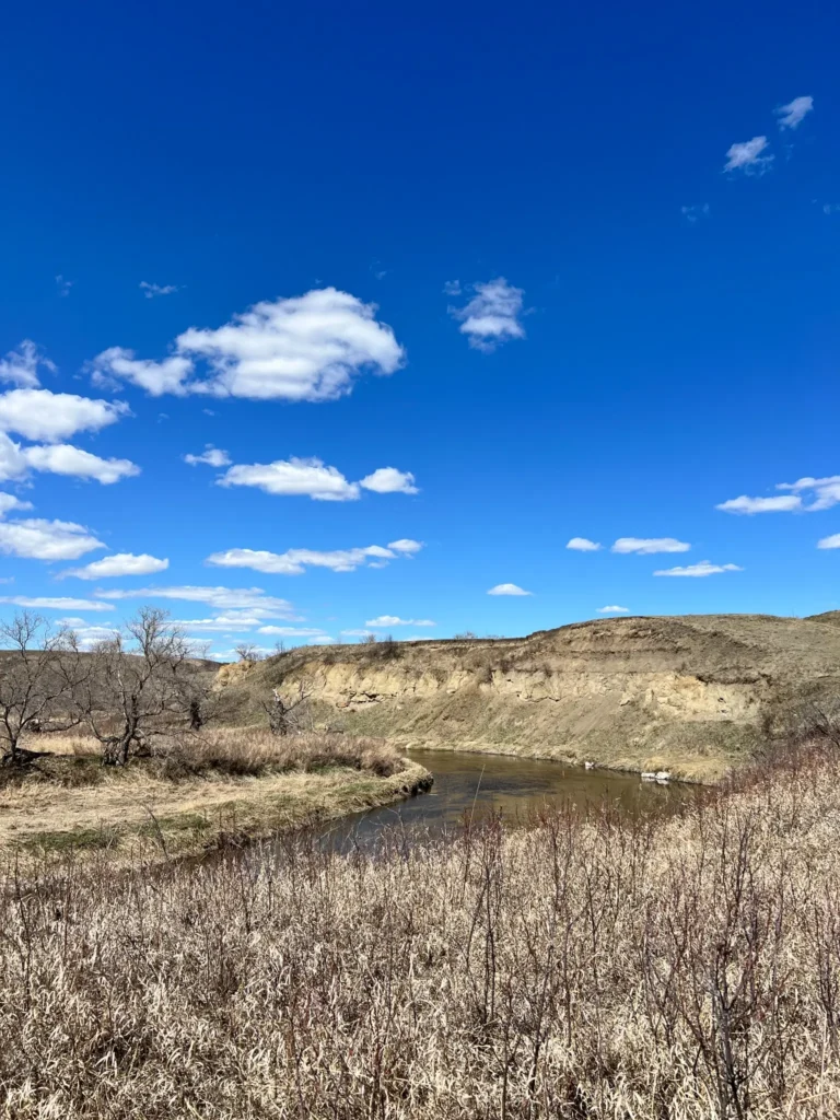 Prairie river beneath a wide blue sky, representing reflection and identity after retirement